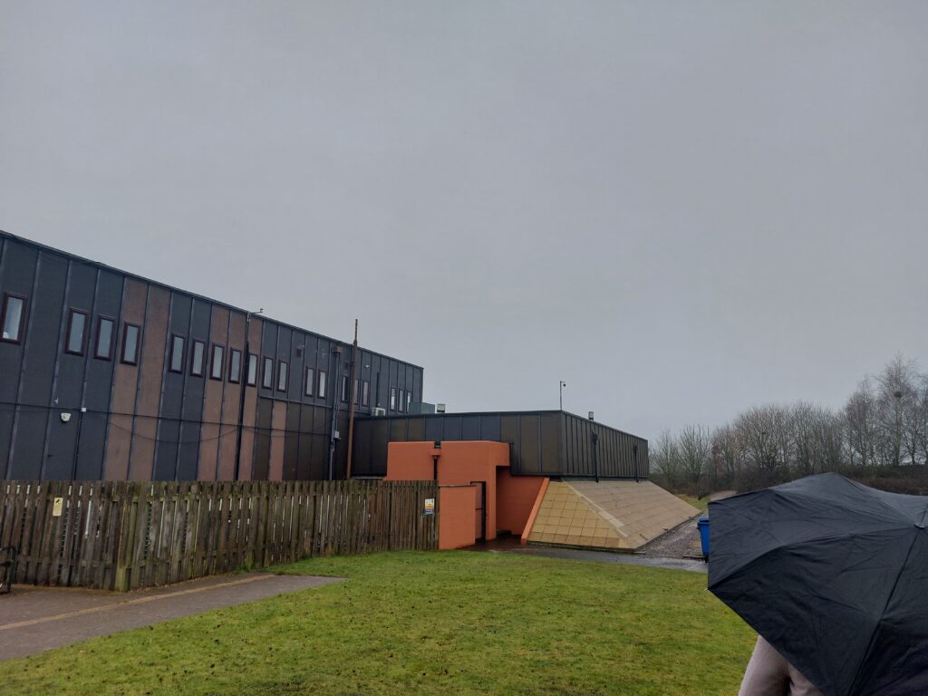 1980s brown building with concrete ballast protecting it