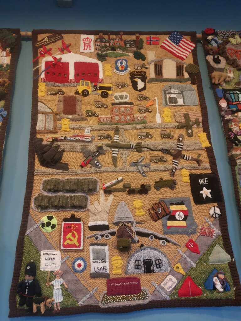 knitted banner showing the protest and airbase