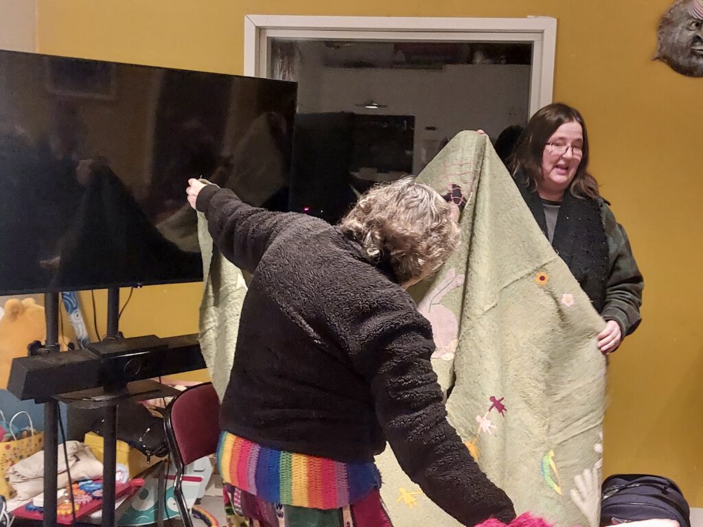 women holding an embroidered blanket