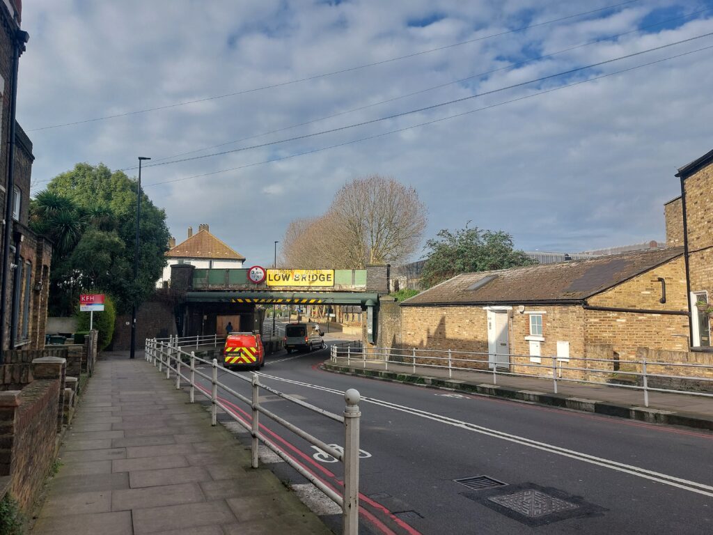 road with a railway bridge and a low bridge sign